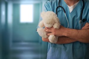Doctor wearing a stethoscope and holding a white teddy bear
