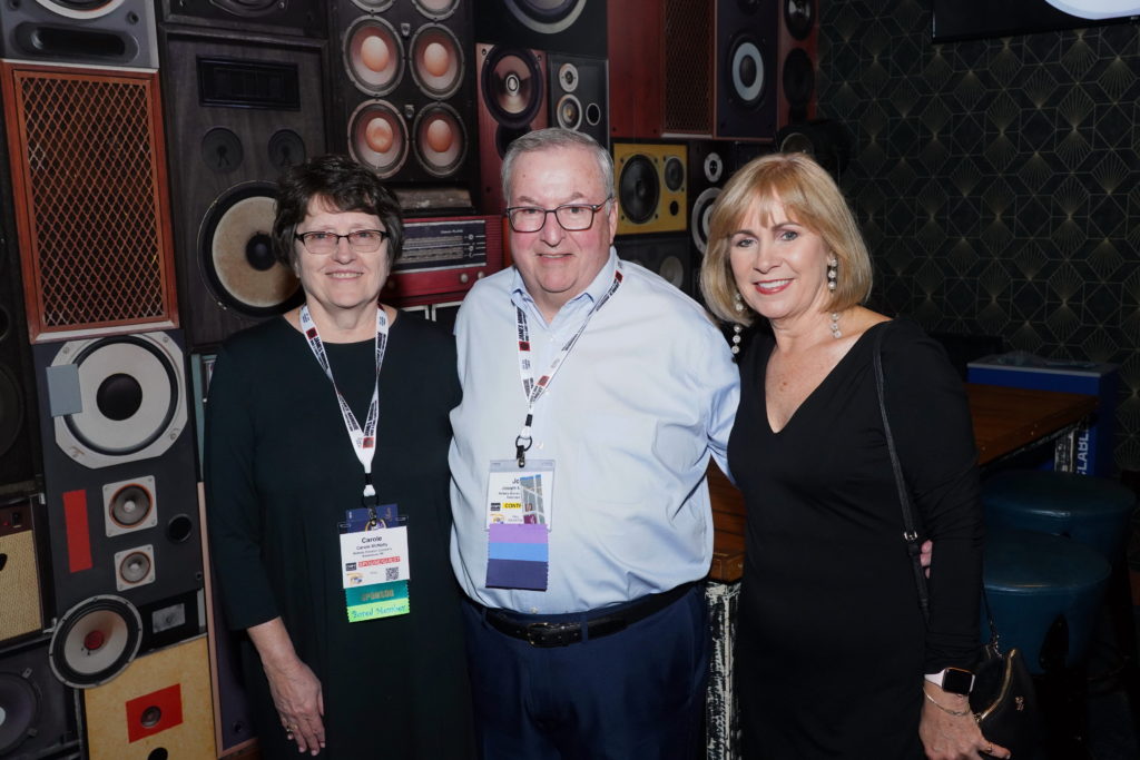 Joe McNally, center, with his wife Carole (left) and Alesa McArthur (right) at he 2019 NAEC Annual Convention in Grand Rapids, Michigan, after Joe accepted NAEC's Sturgeon Award.