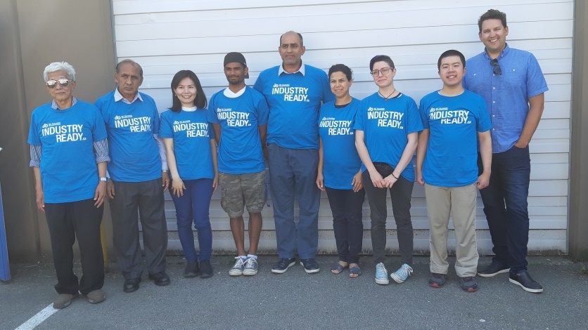 BSIABC Warehouse Certification Program graduates standing in blue shirts in front of a wall