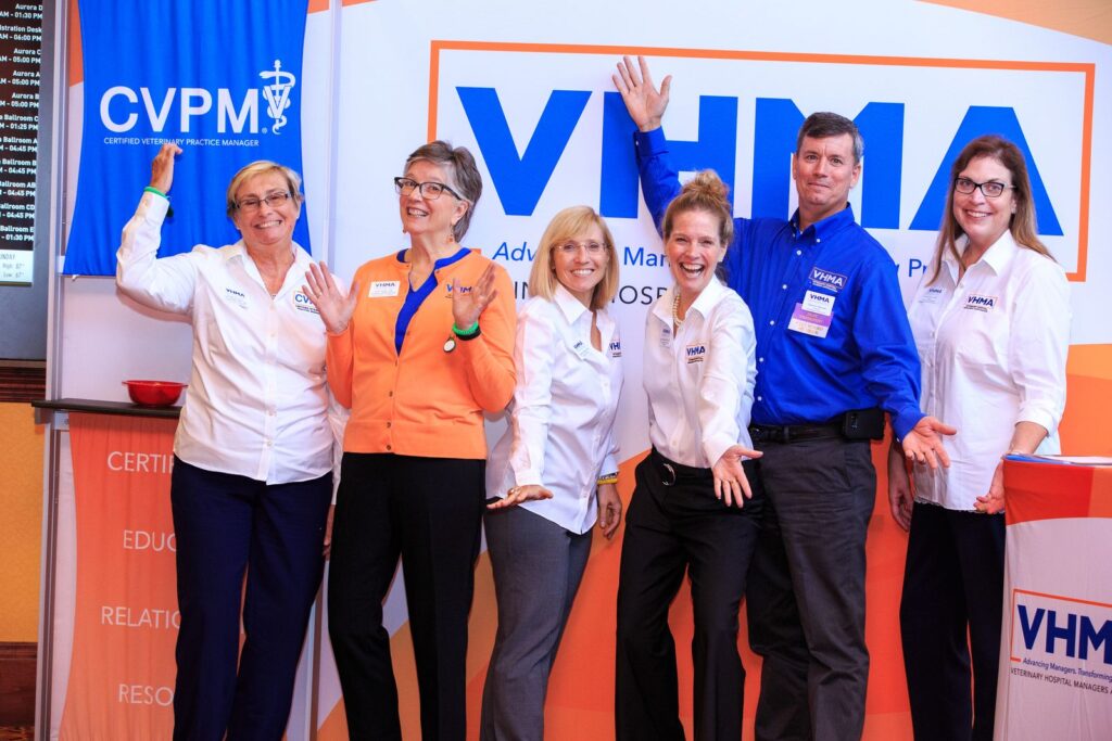 Staff standing in front of a large VHMA sign.