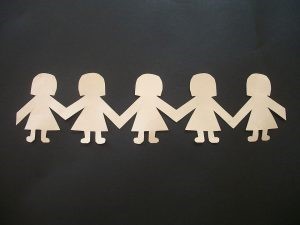 LIght-colored paper doll cutouts on a dark background