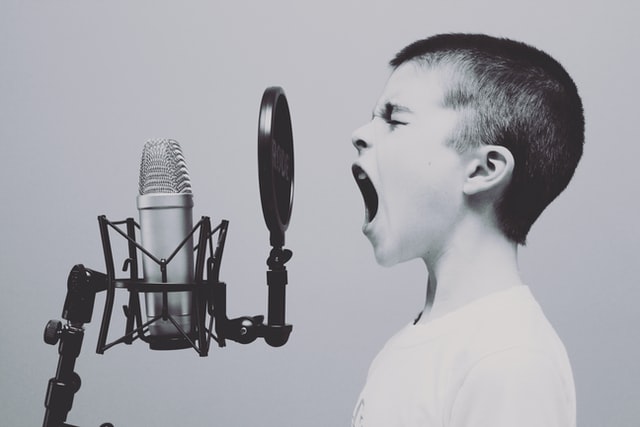 Boy screaming into microphone by Jason Rosewell Unsplash 640px